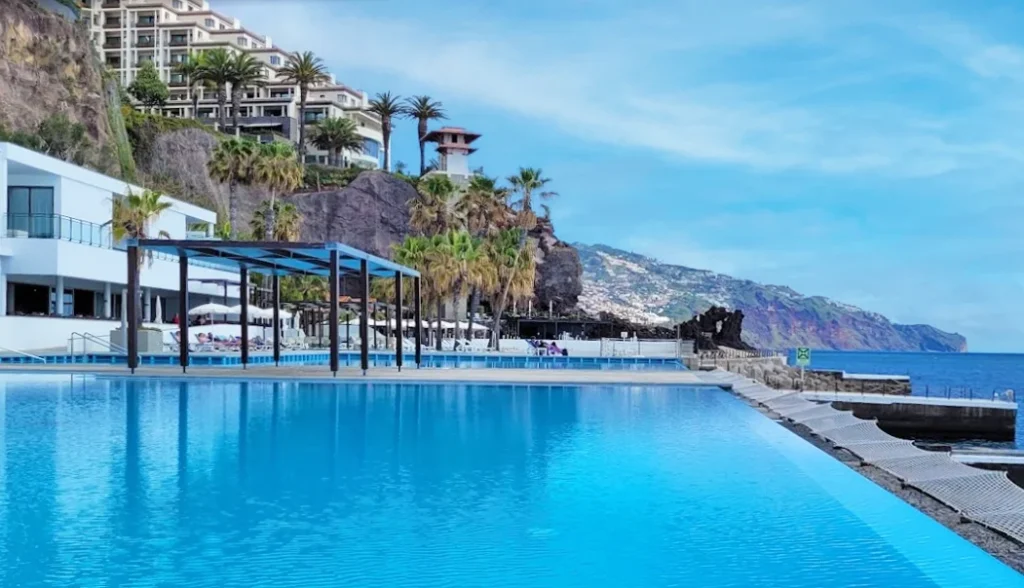 Maravilhosa piscina de hotel com um cenário de mar sereno.
